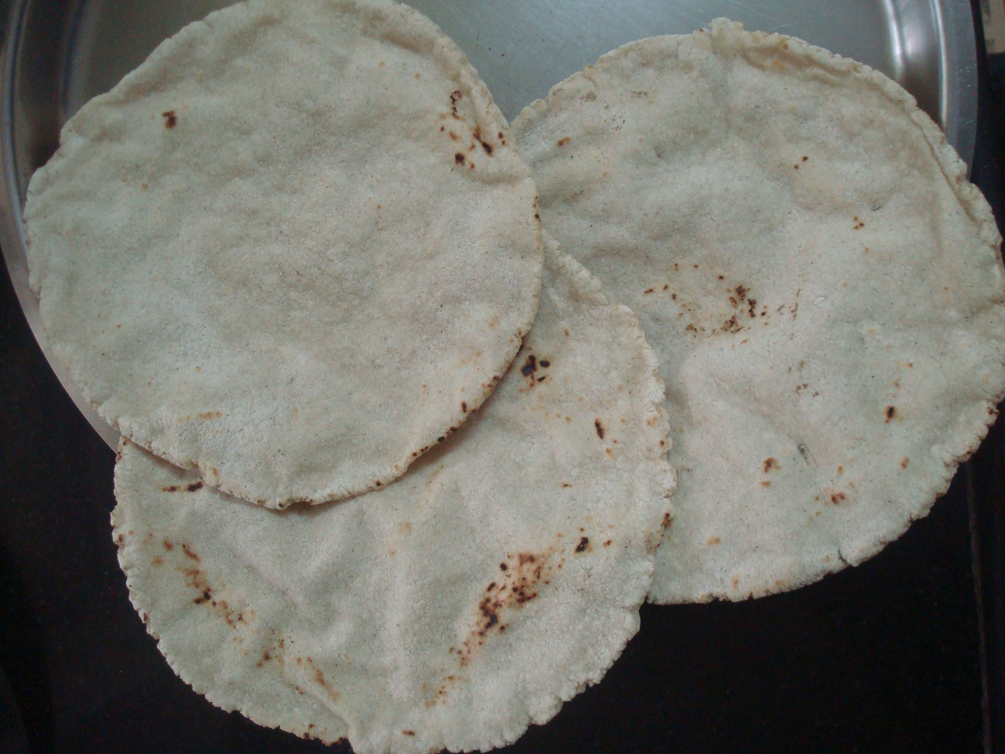 Photograph of bhakri, a type of Indian flatbread, made out of sorghum flour. The photo shows three flat, circular pieces of bread.