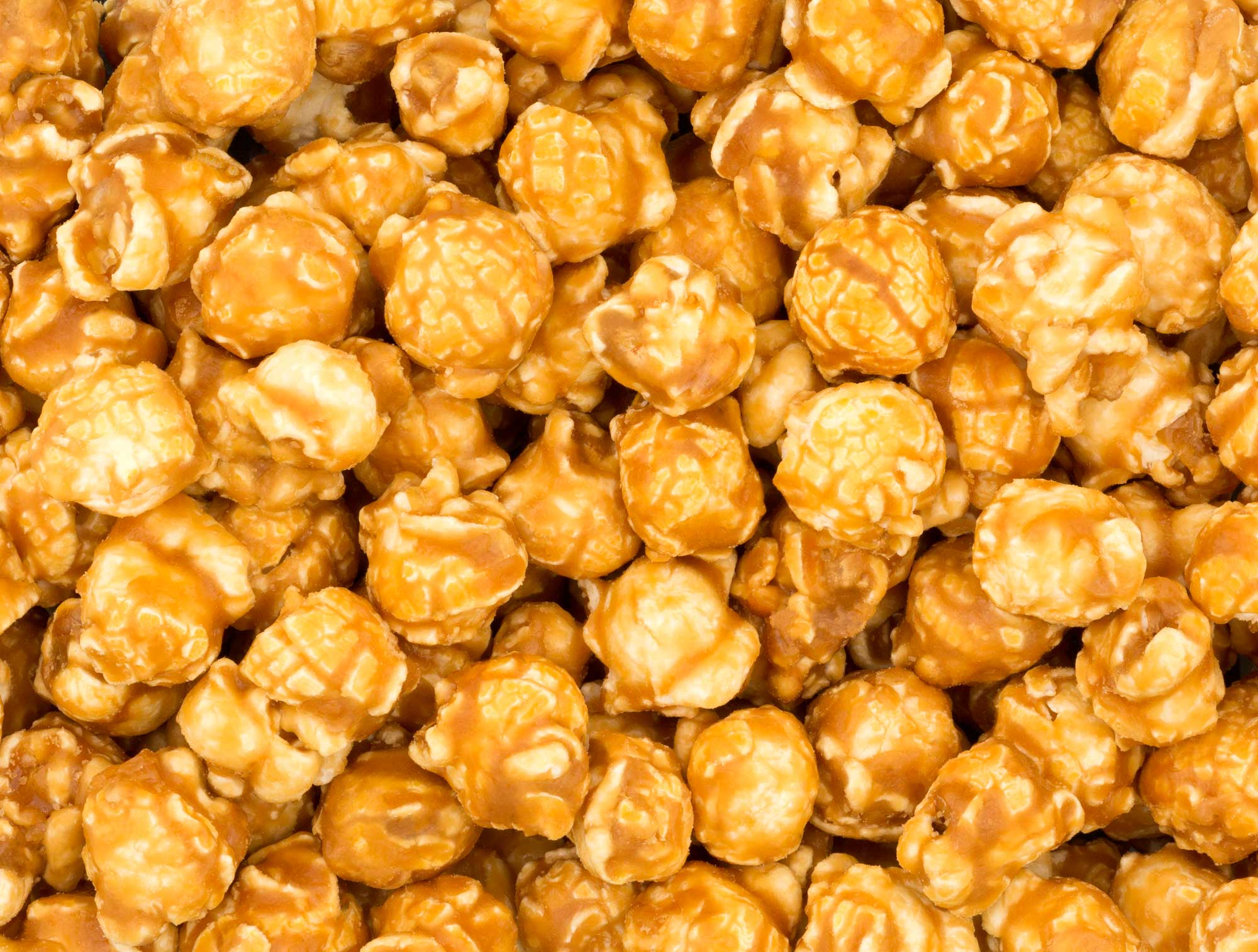 Photograph of caramel corn. The photo shows a detail of popped popcorn kernels covered with a brown caramel coating.