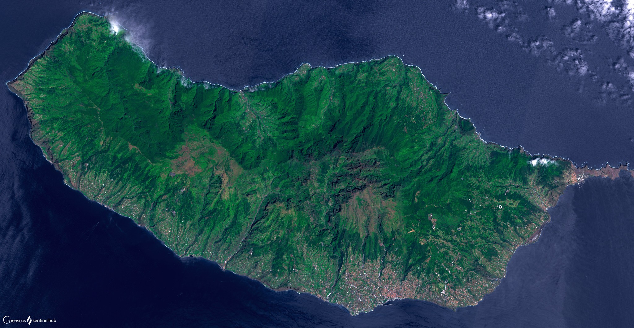 Satellite image fo the Island of Madeira, west of Africa. The image shows a mountainous, green island surrounded by dark blue water.