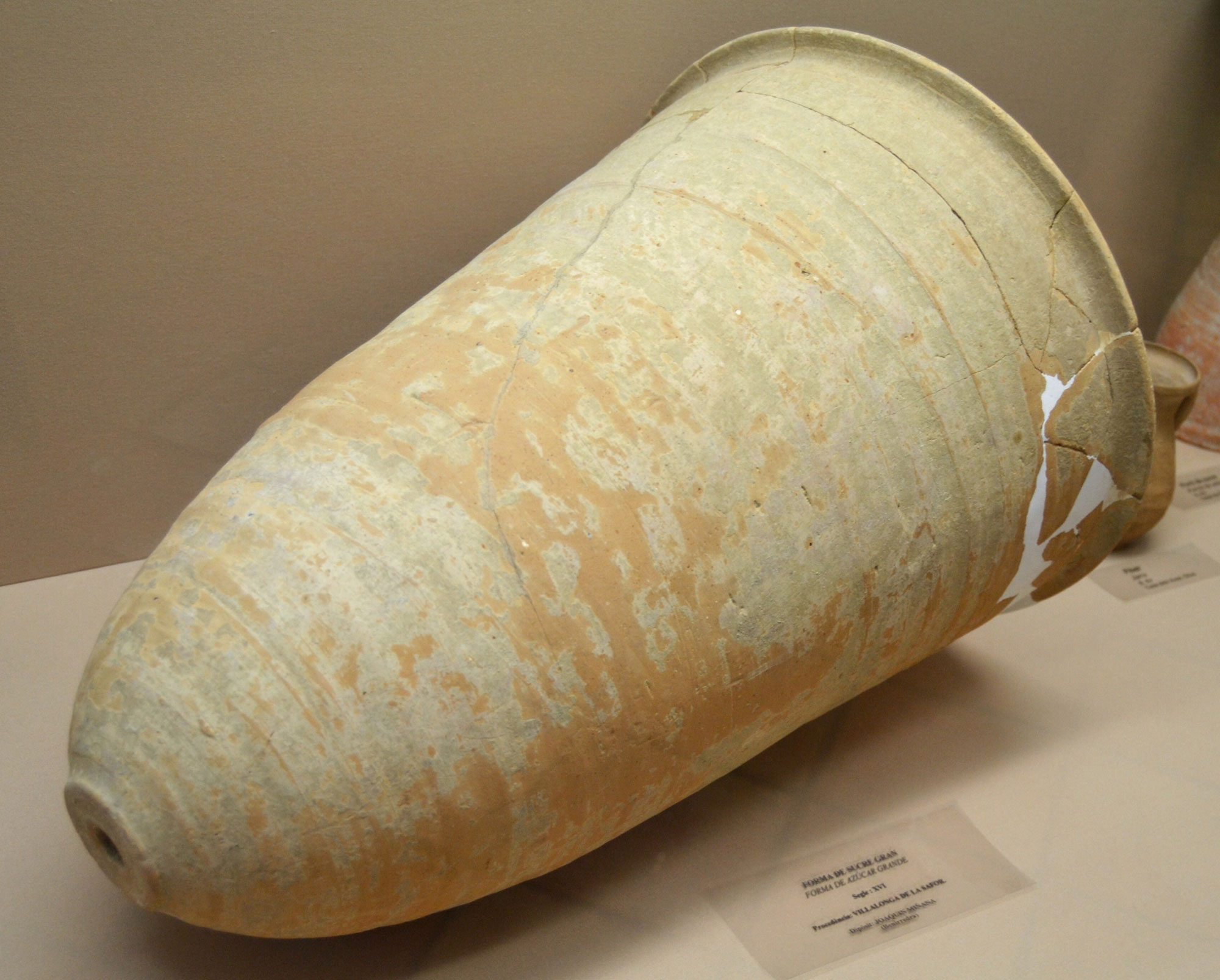 Photograph of a conical ceramic sugar mold from southern Spain dating to the 1500s. The mold has a single hole in the bottom, and the lip has been repaired.