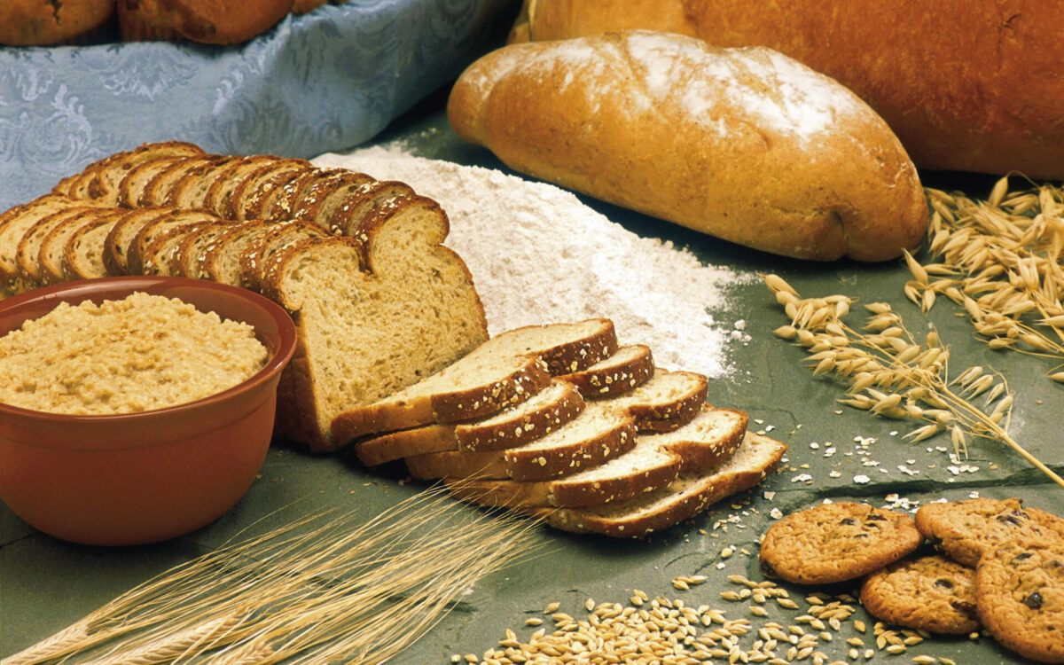 Photograph showing wheat and various products made from wheat, such as cookies, flour, rand bread.