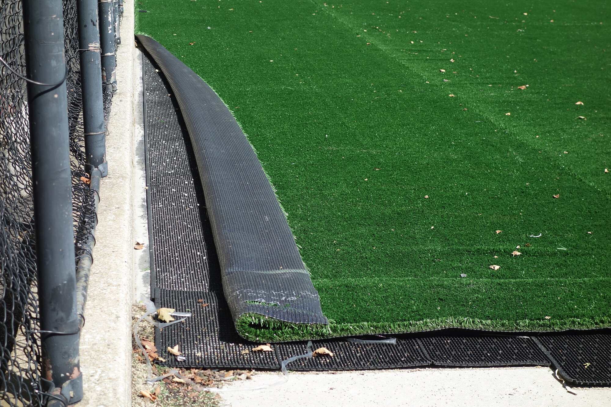 Photograph of the top layers of synthetic turf pealing off the base layer. This turf needs a replacement.