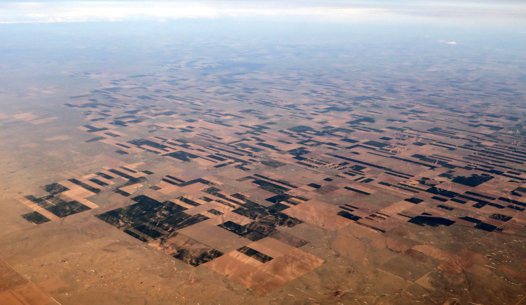Aerial photograph of the region around Arriba, Colorado, in the Great Plains of the United States. The photo shows a relatively flat landscape, most of which has been divided into rectangular agricultural fields that are patches of yellow, brown, or dark green vegetation.
