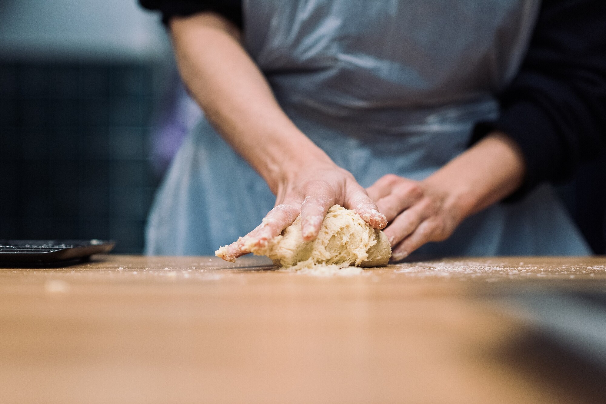 Photograph of the hands of a baker handling dough for bread.
